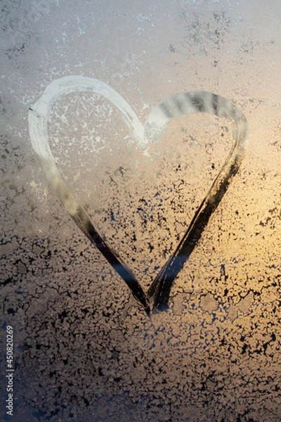 Fototapeta symbol of beautiful heart with the yellow sunlight painted on misted glass, texture of frost and water drops, empty space for an inscription. vertical frame out of focus