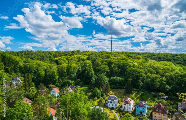 Obraz Germany, Stuttgart television tower building surrounded by green trees of forest on sunny day, aerial panorama drone view above the tree tops and houses