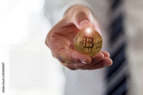 Fototapeta A businessman in a suit is holding a Bitcoin, Cryptocurrency