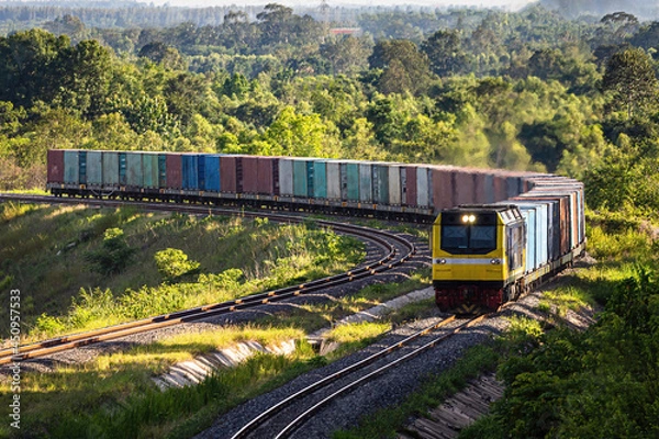 Fototapeta A freight train as it passes through the green fields.