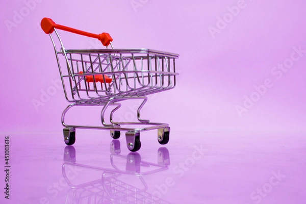 Obraz A small supermarket trolley on a light purple background.