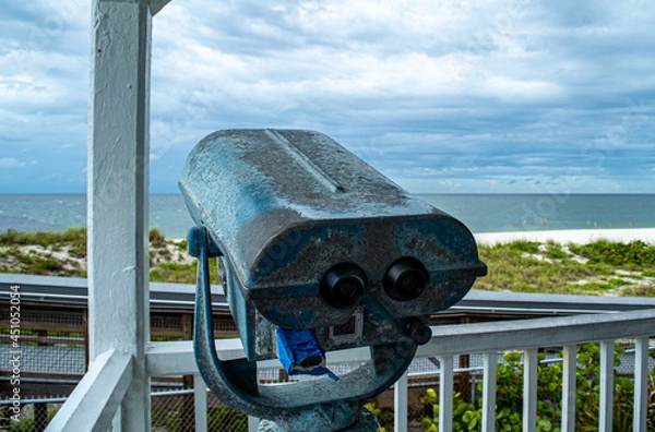 Fototapeta Binoculars view the storm. Port Boca Grande Lighthouse and Museum stand strong on Gasparilla Island as a tropical storm with black clouds loom of the coast in the Gulf of Mexico