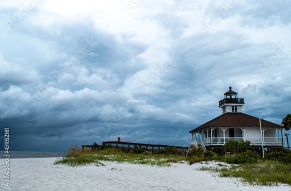 Obraz Port Boca Grande Lighthouse and Museum stand strong on Gasparilla Island as a tropical storm with black clouds loom of the coast in the Gulf of Mexico