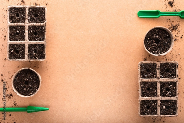 Fototapeta Peat pots and peat trays filled with potting soil and sowing tools on a raw surface with copy space