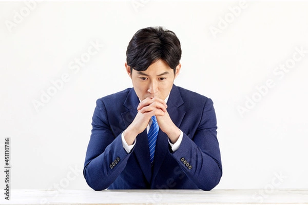 Obraz 흰 배경 앞에 정장 입은 고민하는 30대 한국 남자