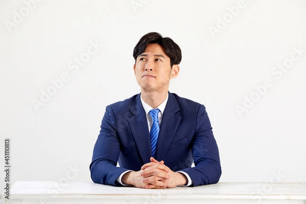 Obraz 흰 배경 앞에 정장 입은 고민하는 30대 한국 남자