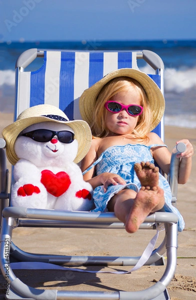 Fototapeta Ребенок сидит на шезлонге с игрушкой