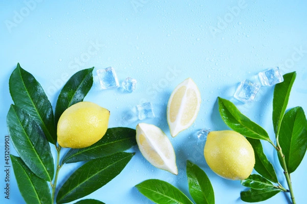 Fototapeta Frame, lay out ice cubes, lemons with green leaves and water drops on the blue background. Summer vibes. Cooling fresh humid template composition. Empty space for text on the top. Flyer, card.