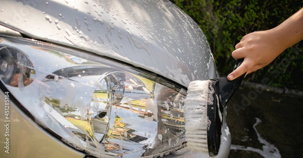 Fototapeta Man washing a car with a brush