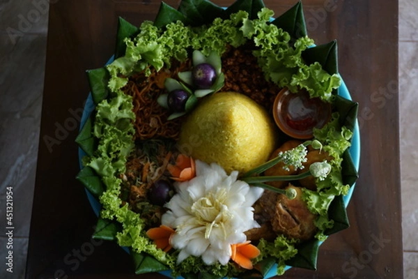 Fototapeta Cone-shaped yellow rice is an Indonesian traditional food, called Nasi Tumapeng. A lively Indonesian rice dish with side dishes.