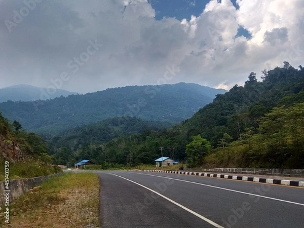 Fototapeta wide highway and blue sky and white clouds and mountains background
