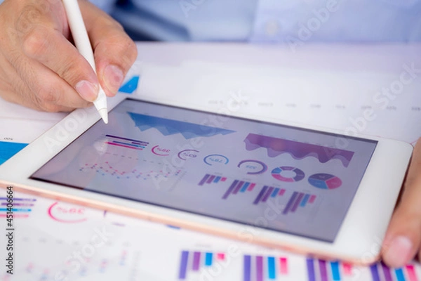 Obraz Businessman planning about graph and chart of investment with report for finance on tablet computer on desk, statistic for financial and profit with document, digital marketing, business concept.