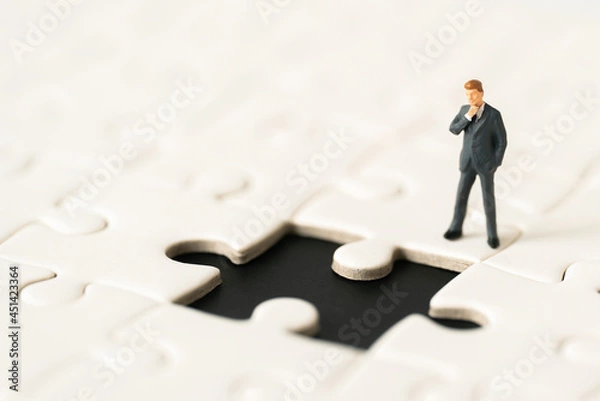 Fototapeta Miniature people Group Business man mini figures standing thinking on Jigsaw Puzzle white background copy space using as thinking business plan and how to solve problem Strategy Planning concepts