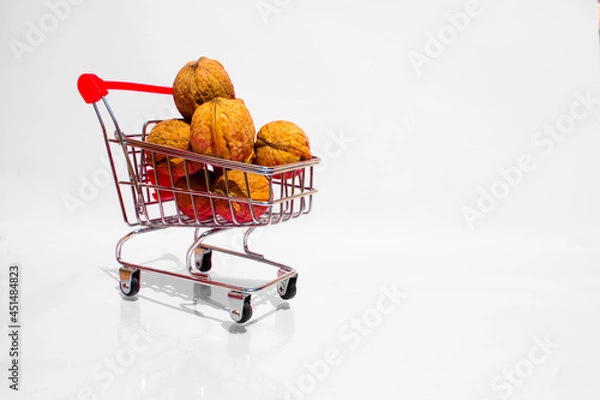 Fototapeta A small cart full of walnuts on a white background