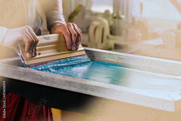 Fototapeta serigraph printing production. silk screen textile printery. manual screen printing design studio. photo of male hands with squeegee