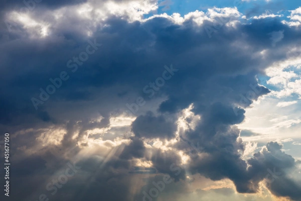 Fototapeta Evening sun rays through thick clouds. Bright view of natural colorful background at sunset.