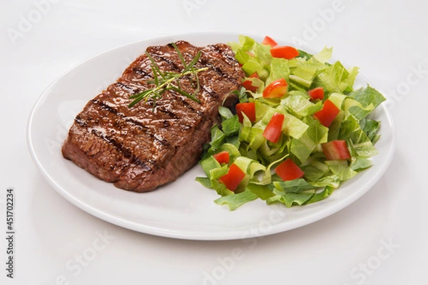 Obraz Delicioso corte de carne bovina grelhada com salada de alface picada com tomate e pepino. No fundo branco para recorte.