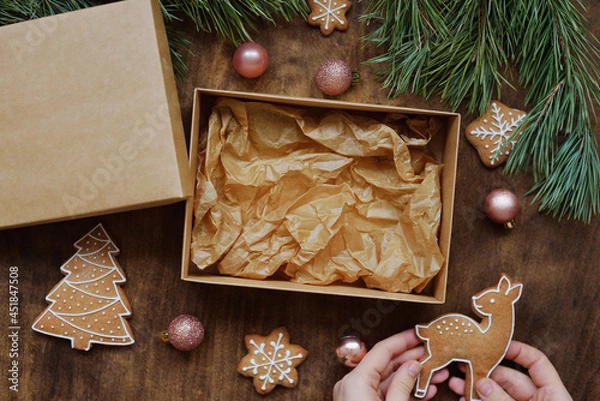 Obraz empty kraft box with brown lid for sweets, cookies on New Year's table with gingerbread for home delivery from pastry shop. new year food delivery concept.