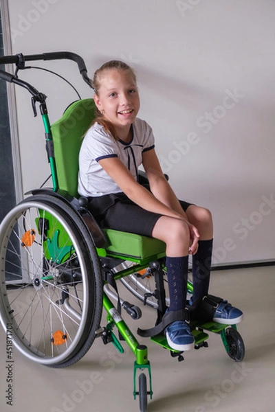 Fototapeta Special child on wheelchair. Girl in school uniform on the background of the school board.