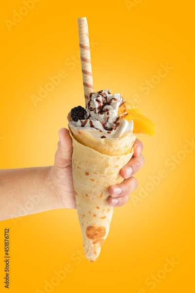 Obraz Crepe with mango in hand on yellow background