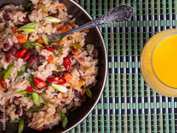 Obraz Gallo pinto, Costa Rican rice with beans and hot peppers in a plate, top view with orange juice in a glass