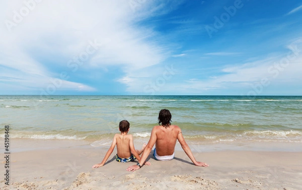 Obraz Отец и сын сидят на пляже.