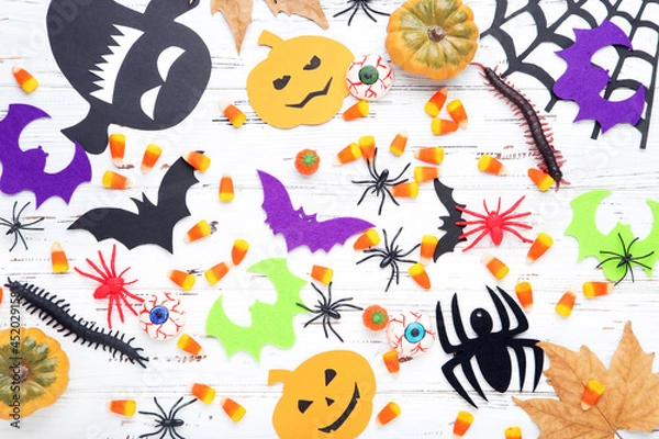 Fototapeta Halloween pumpkins, candies, paper ghosts, bats, spiders and maple leaf on wooden background