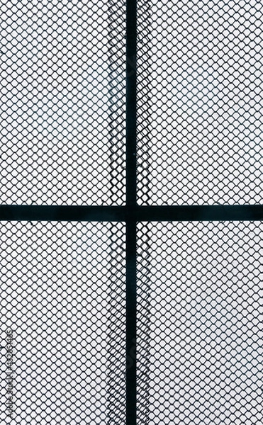 Fototapeta Metal chain link fence pattern straight on. Silhouetted by sky.