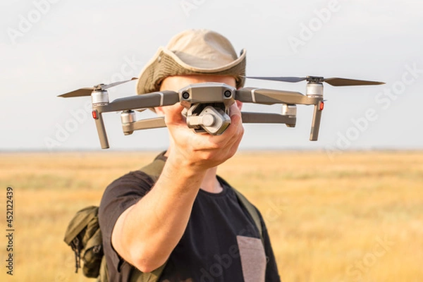 Obraz a tourist guy launches a quadcopter and holds it in his hand