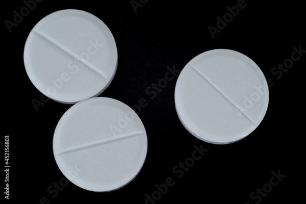 Fototapeta white, round pills on a black background. macro photo