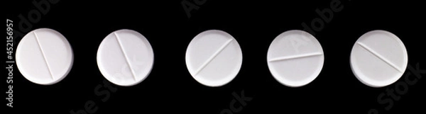 Fototapeta white, round pills on a black background. macro photo