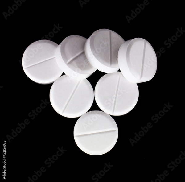 Fototapeta white, round pills on a black background. macro photo