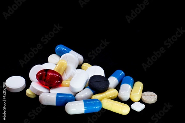 Fototapeta pills of different shapes and colors on a black background. macro photo
