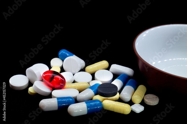 Fototapeta pills of different shapes and colors on a black background. macro photo