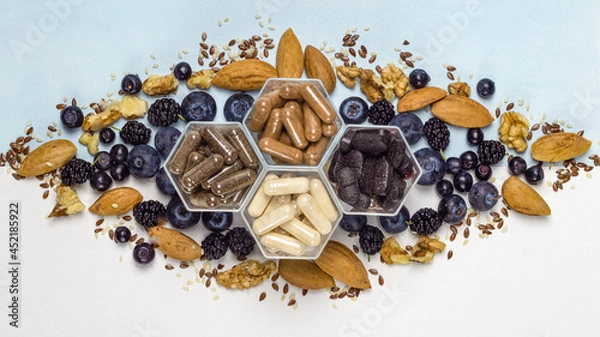 Fototapeta Various capsules with dietary supplements or vitamines and fresh blueberry and nuts