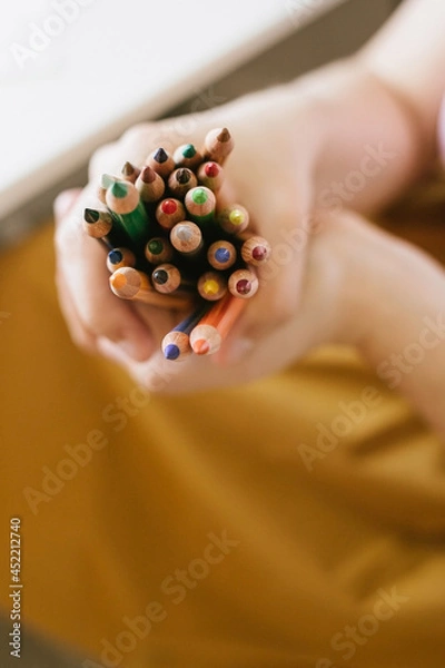 Fototapeta a bunch of colour pencils in woman's hands on yellow background, back to school concept