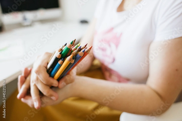 Fototapeta a bunch of colour pencils in woman's hands , computer desk in background