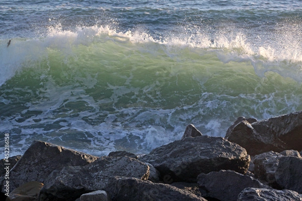 Obraz Sea wave during a storm with foam on the background of stones.