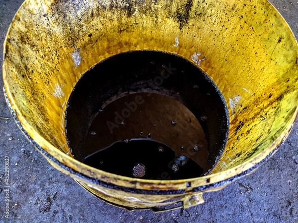 Fototapeta old dirty bucket with used engine oil in the garage.