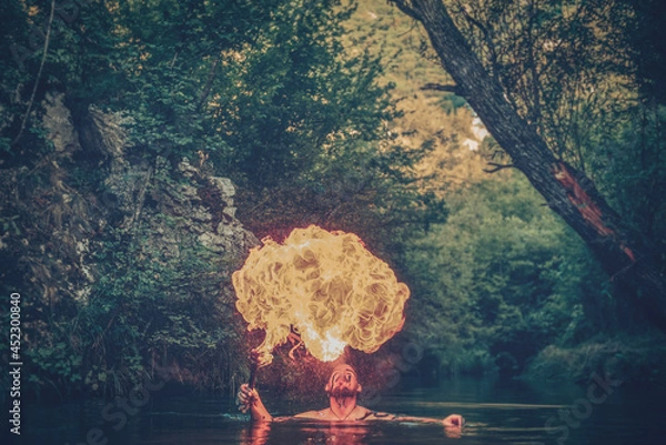 Fototapeta Man in a river blowing fire