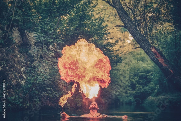 Fototapeta Man in a river blowing fire