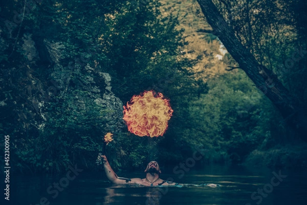 Fototapeta Man in a river blowing fire