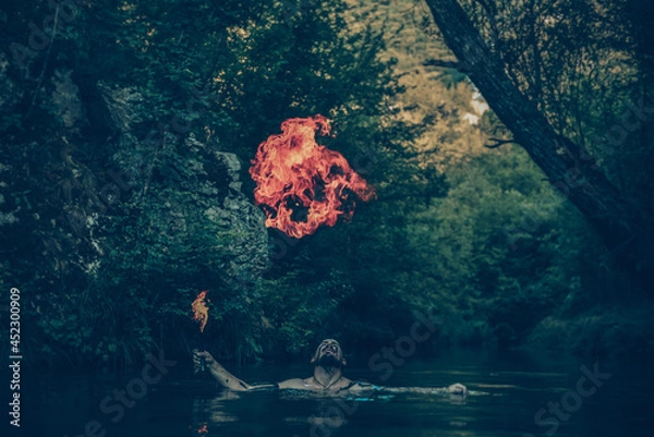 Fototapeta Man in a river blowing fire