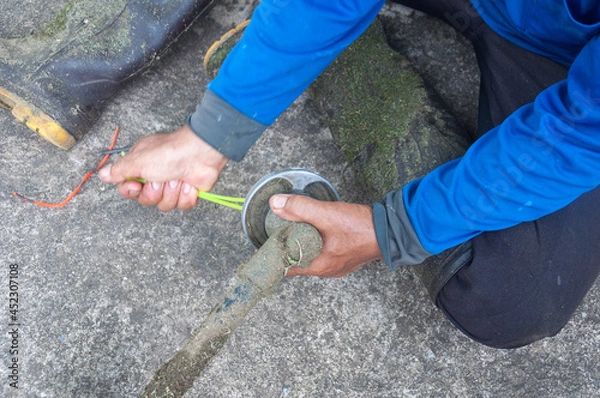 Fototapeta Close up on Gardener's hand holding a trimmer head and repairing weed cutter replacing parts replacement 