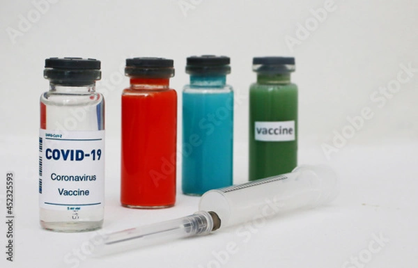 Fototapeta Four ampoules with vaccine and medicines and a syringe on a light background.
