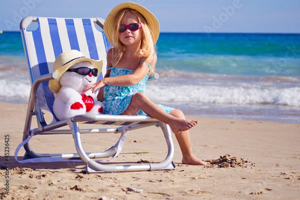 Fototapeta девочка сидит на шезлонге на берегу моря