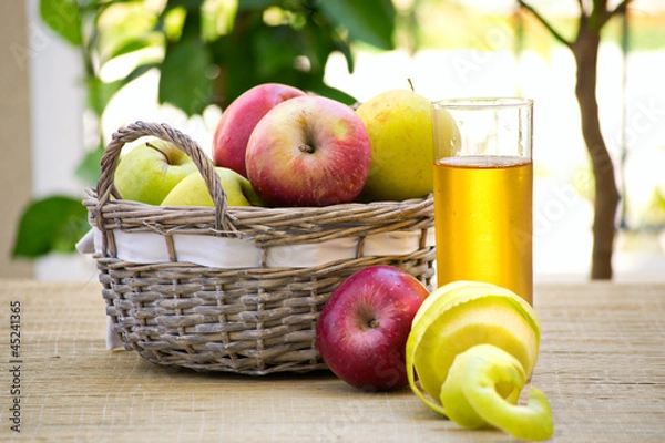 Fototapeta корзинка с яблоками и стакан сока стоят на столе