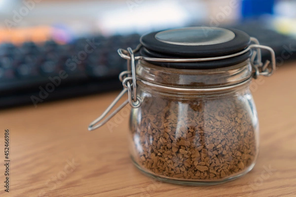 Fototapeta Instant coffee in a glass jar on a desktop on a keyboard background