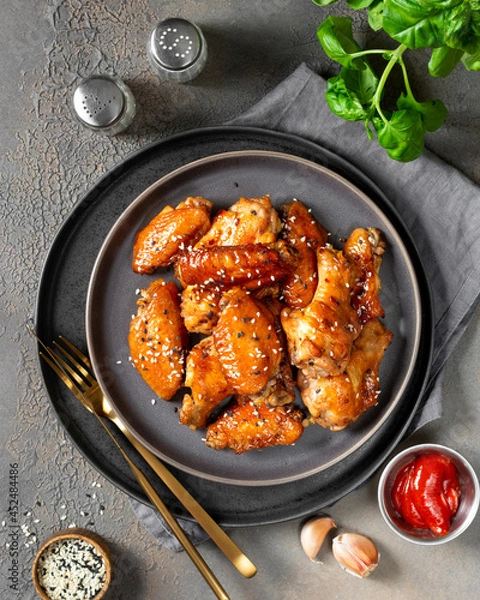 Obraz Homemade baked or fried chicken wings in barbecue sauce in a plate on the cooking table top view