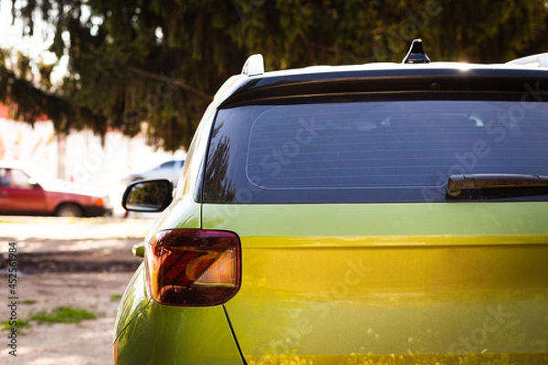Fototapeta Back window of green car parked on the street in summer sunny day, rear view. Mock-up for sticker or decals